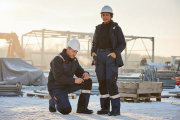 Workers wearing thermal workwear trousers on a snowy construction site for cold weather protection